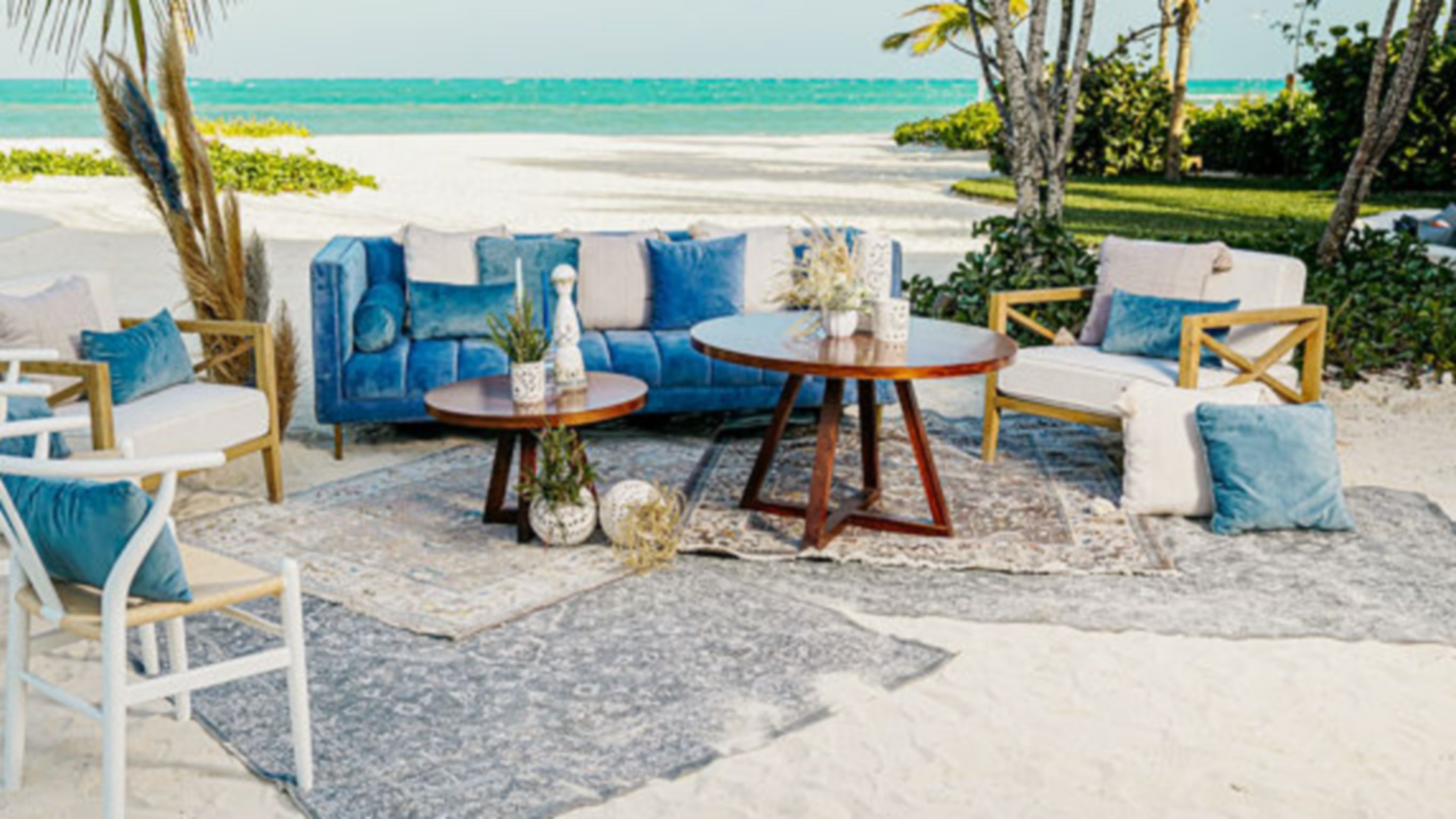 Event setup with blue lounge furniture and rugs on beach