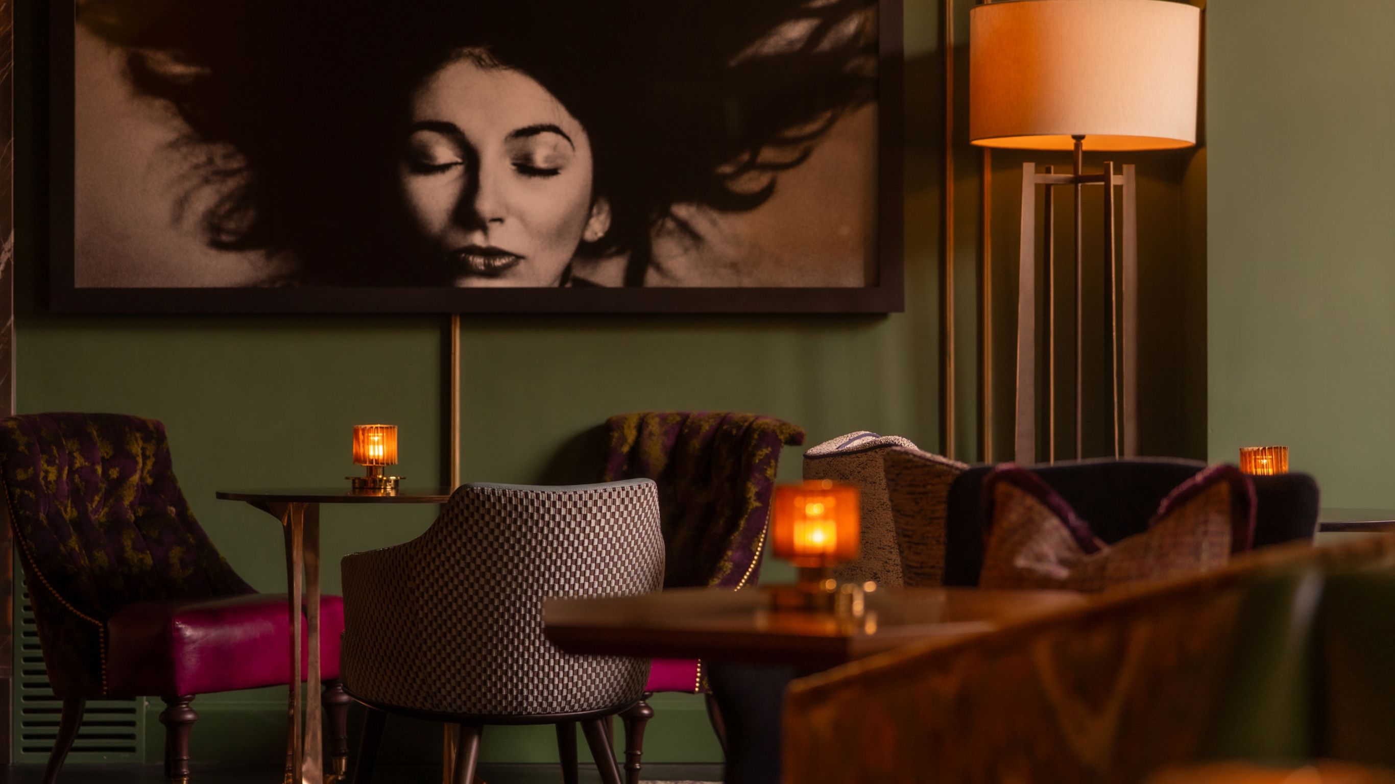 A section of the bar with seating that includes chairs, small tables, and a framed photograph on the wall.