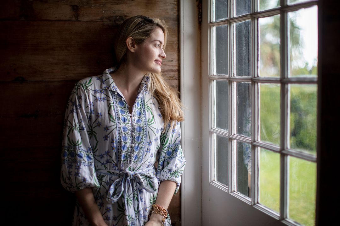 sarah bray peering through antique glass pane windows of verdmont heritage home