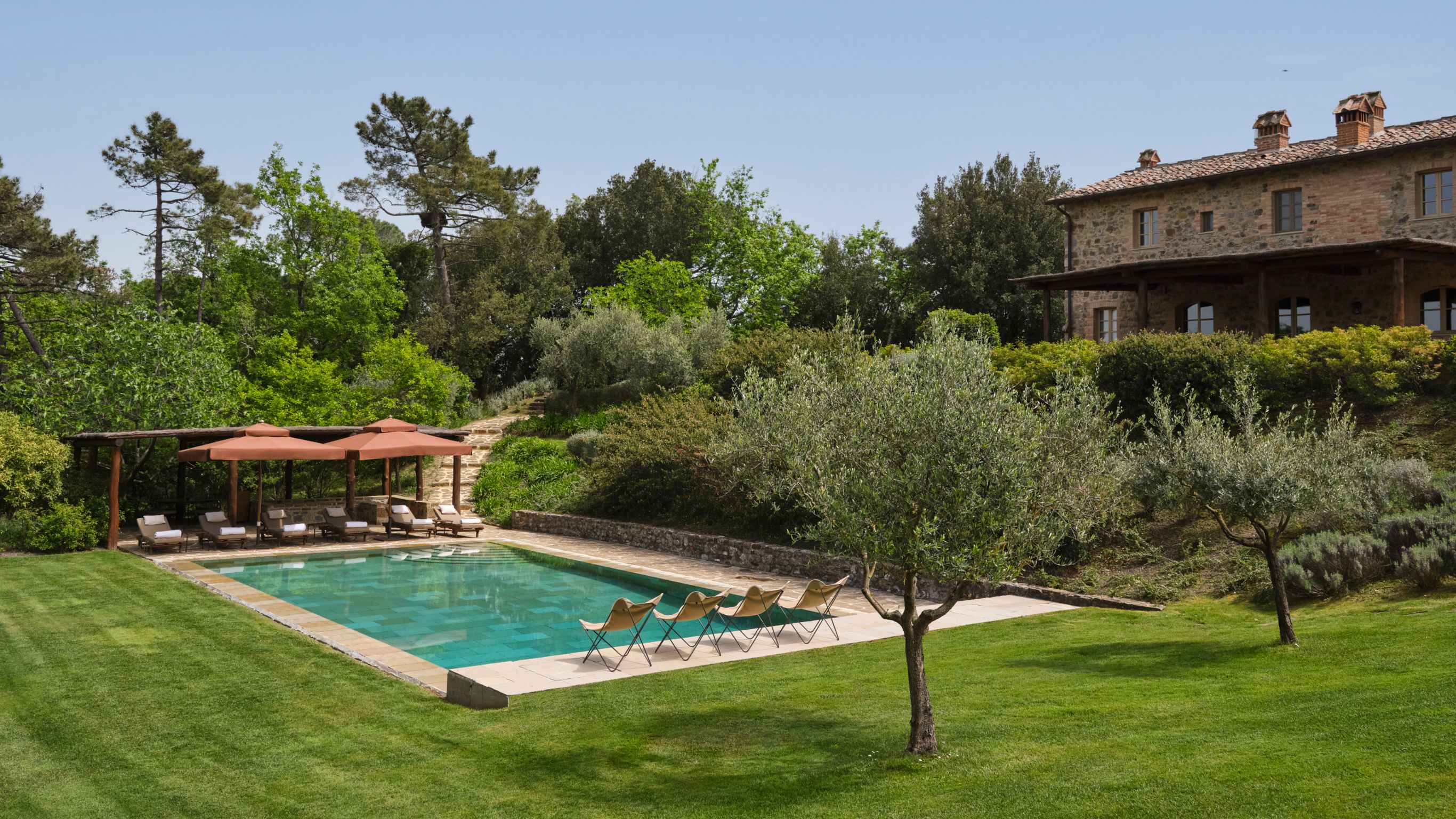 A countryside villa pool area with lounge  chairs and greenery