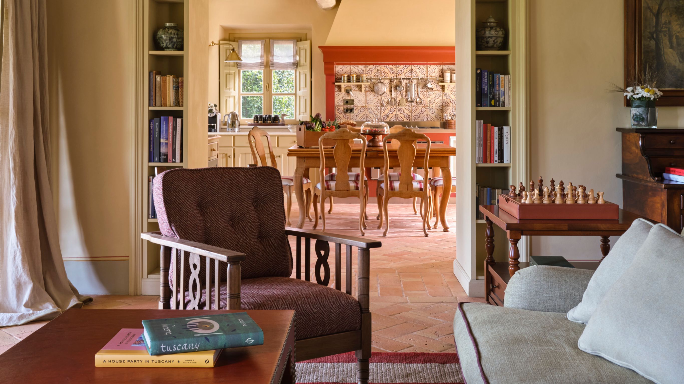 A Tuscan living room with warm tones, rustic  furniture, and a view to a kitchen