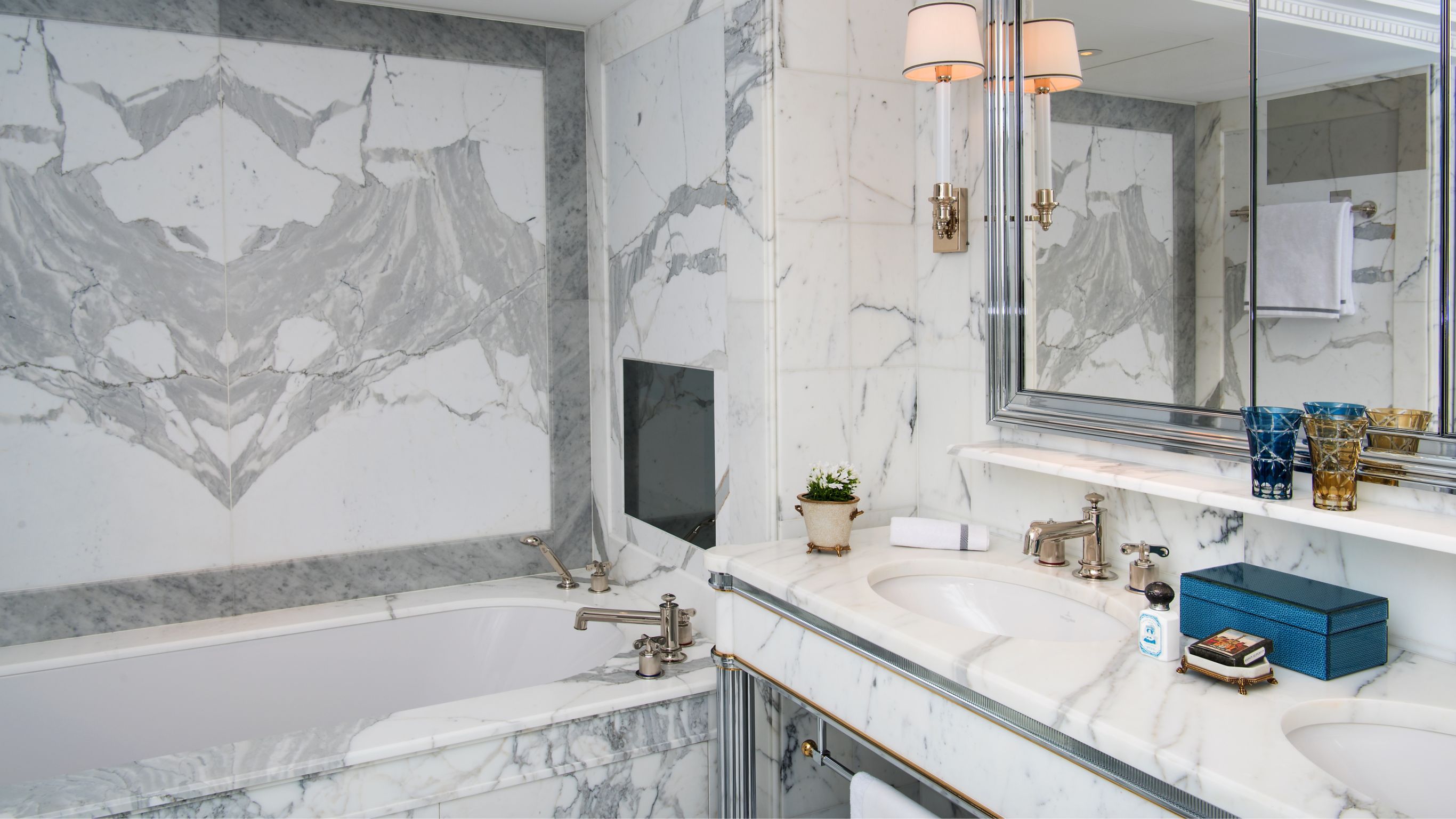 Marble bathroom featuring a double vanity with a built-in bathtub and a large mirror.