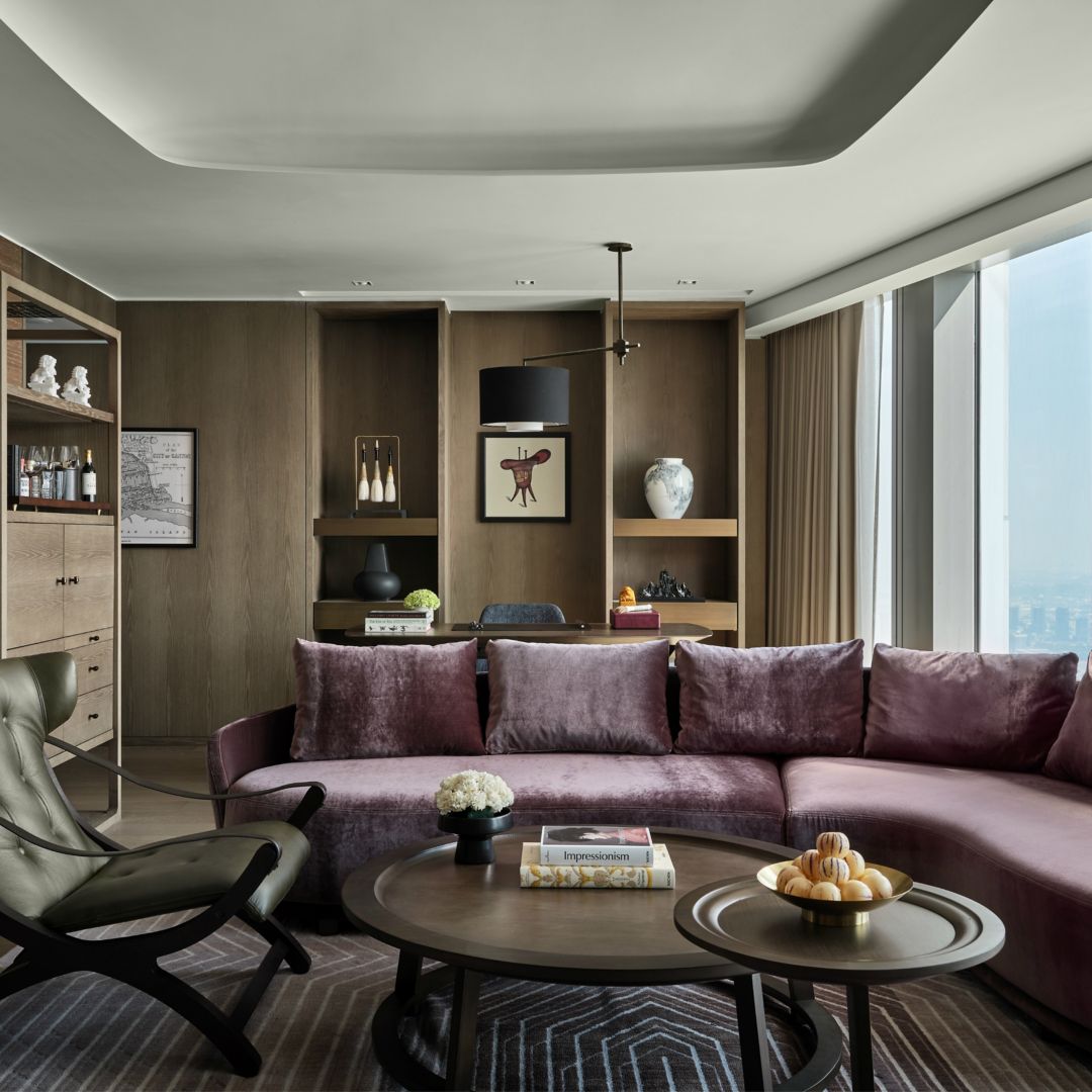 Elegant luxury hotel suite with plush modern furniture, floor-to-ceiling windows, and refined decor.