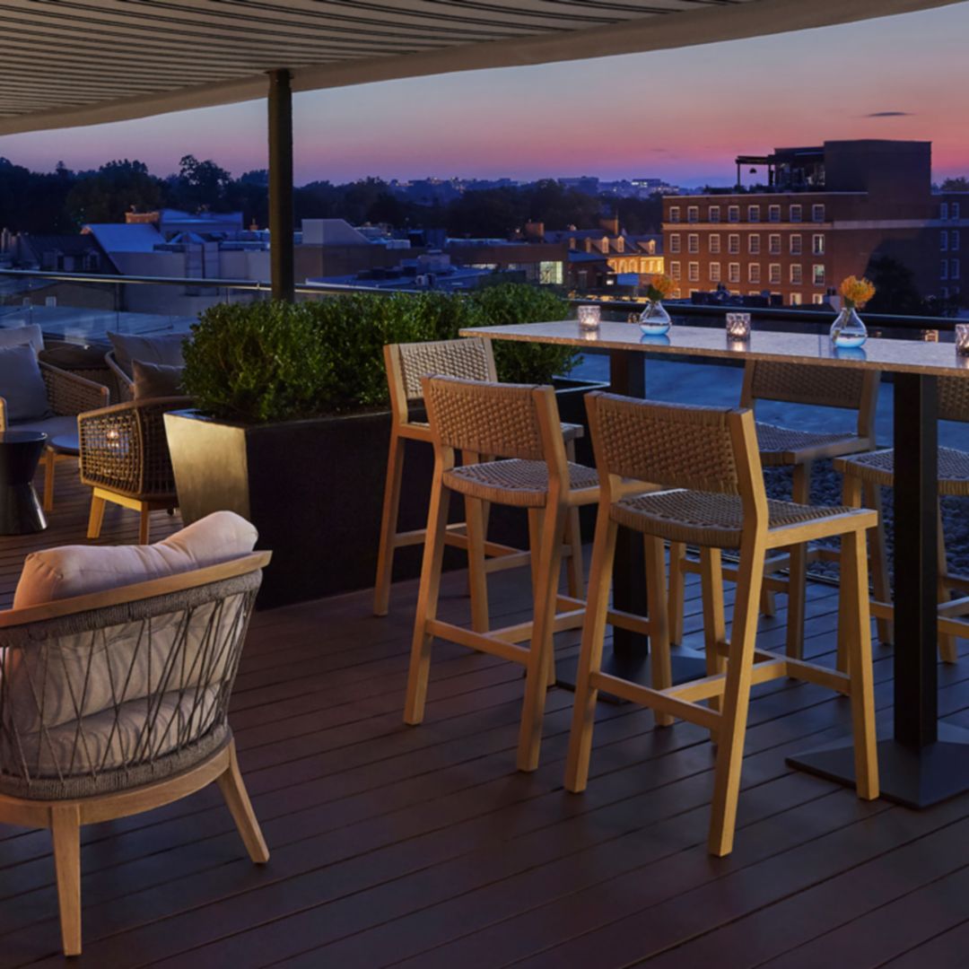 A rooftop restaurant in D.C. at dusk with wooden furniture.