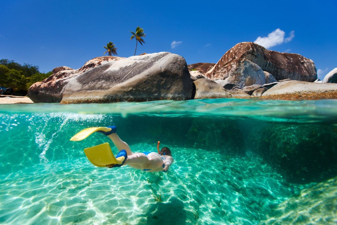 Underwater view of a woman snorkeling with yellow swimfins.