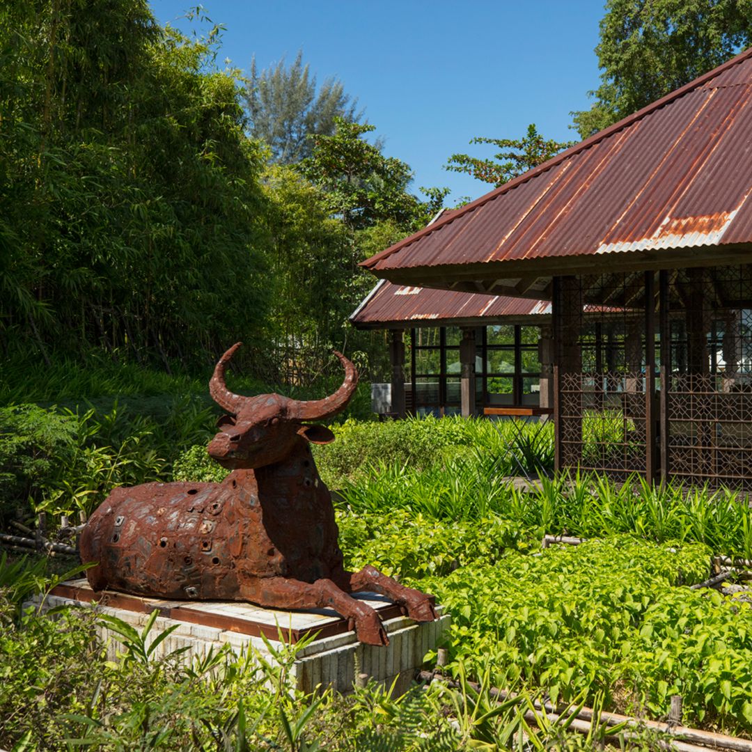 A garden area with a sculpture of a bull, surrounded by plants.