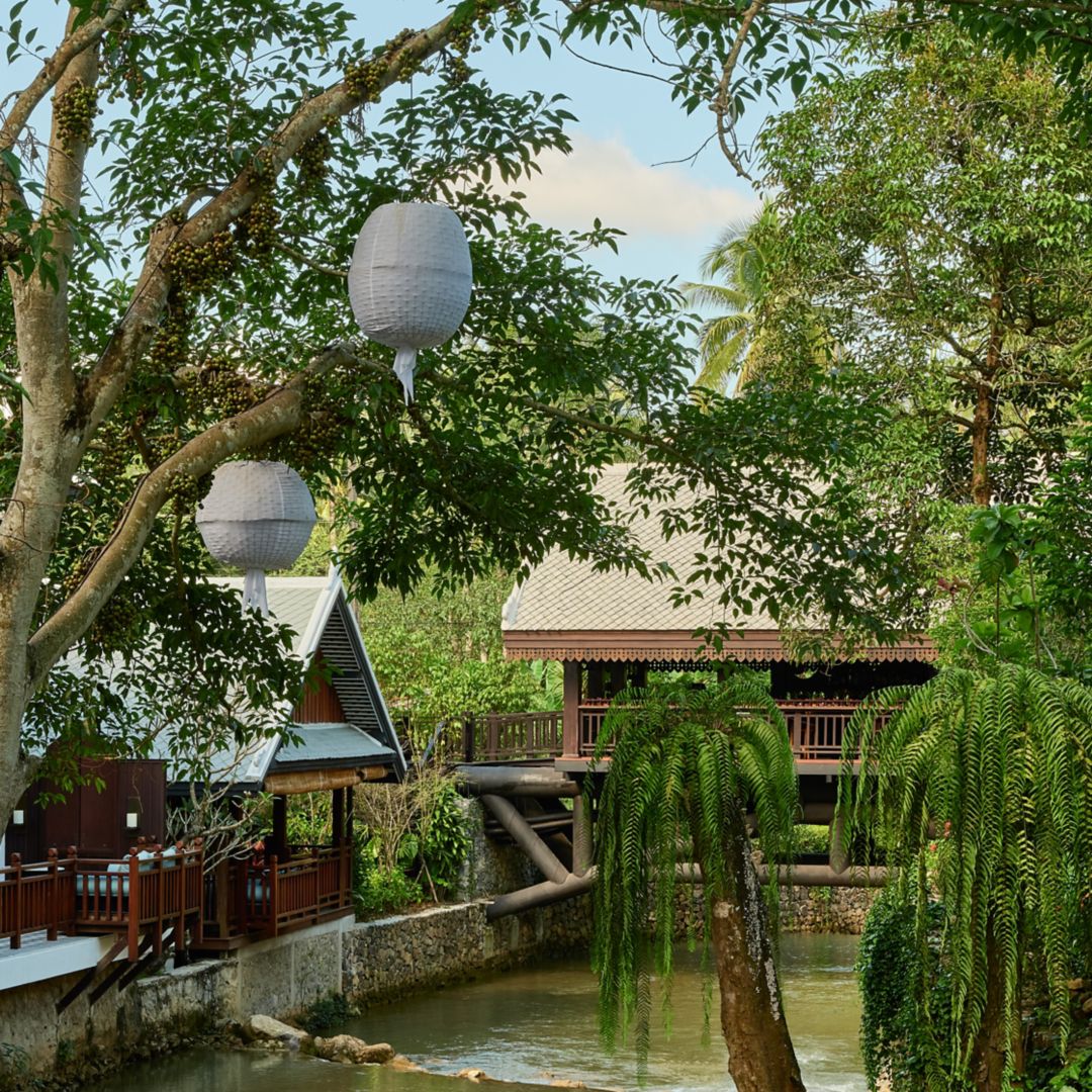 The Elephant Bridge Bar, viewed from outside, features two distinct seating cabins surrounded by lush trees with hanging paper lanterns.The Elephant Bridge Bar, viewed from outside, features two distinct seating cabins surrounded by lush trees with hanging paper lanterns.