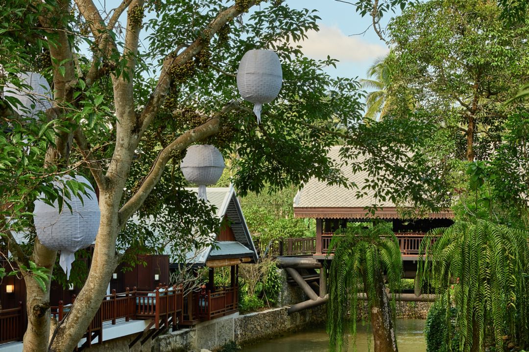 The Elephant Bridge Bar, viewed from outside, features two distinct seating cabins surrounded by lush trees with hanging paper lanterns.The Elephant Bridge Bar, viewed from outside, features two distinct seating cabins surrounded by lush trees with hanging paper lanterns.
