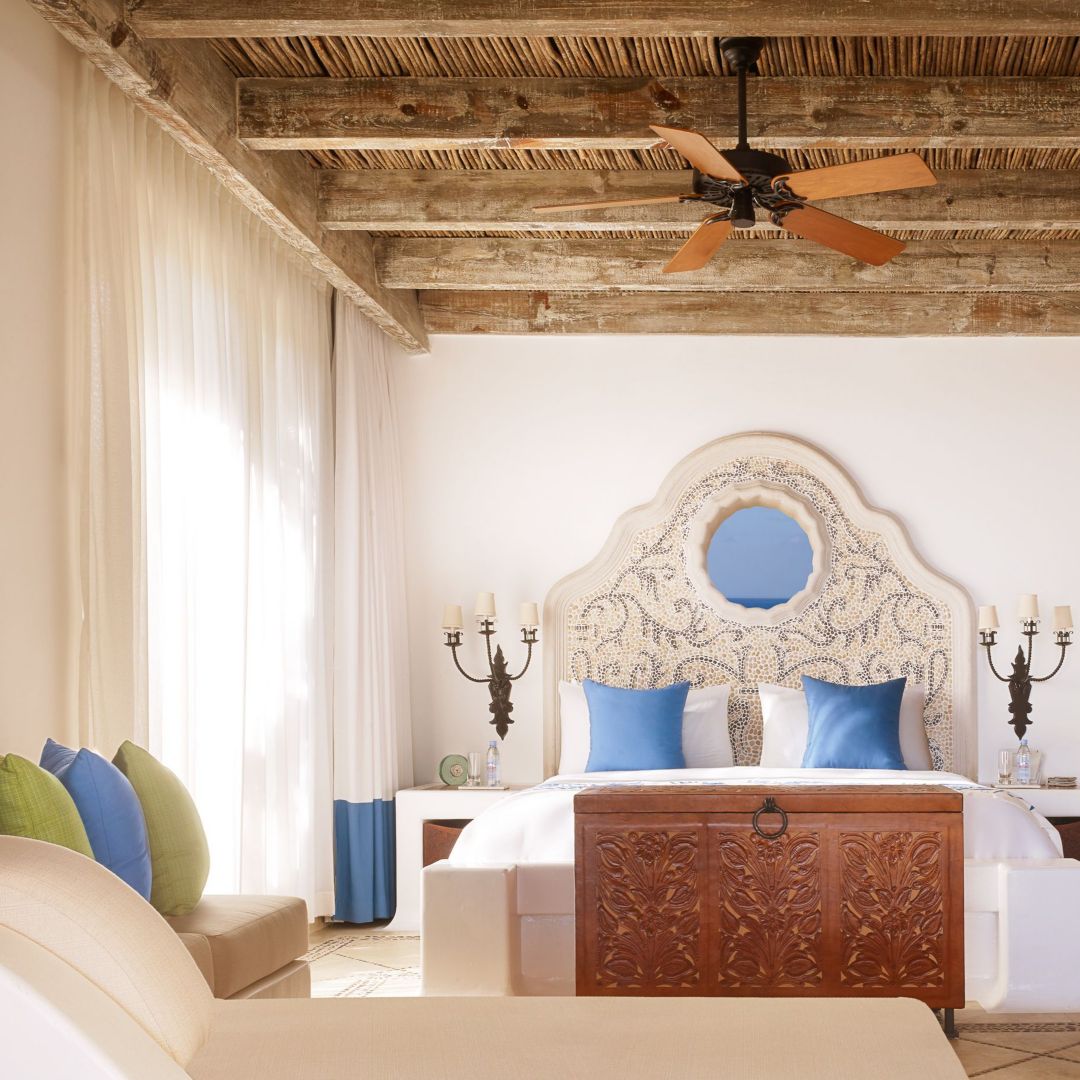 A Cabo residence featuring a bed with an ornate headboard and a wooden chest at its foot.