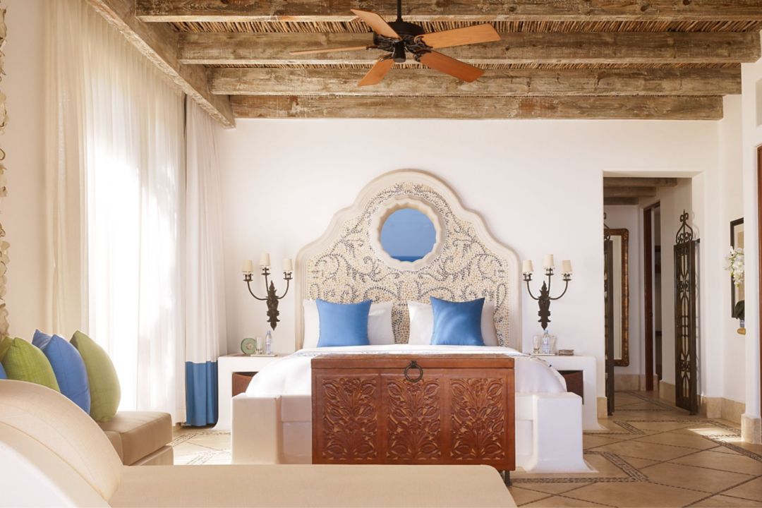 A Cabo residence featuring a bed with an ornate headboard and a wooden chest at its foot.