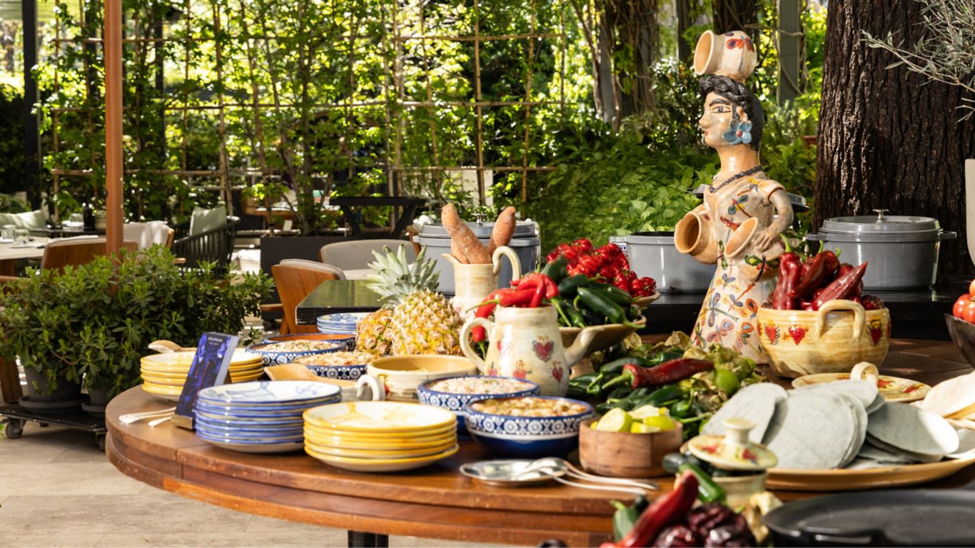 estacion mexicana con decoracion y platos mexicanos en una terraza ajardinada