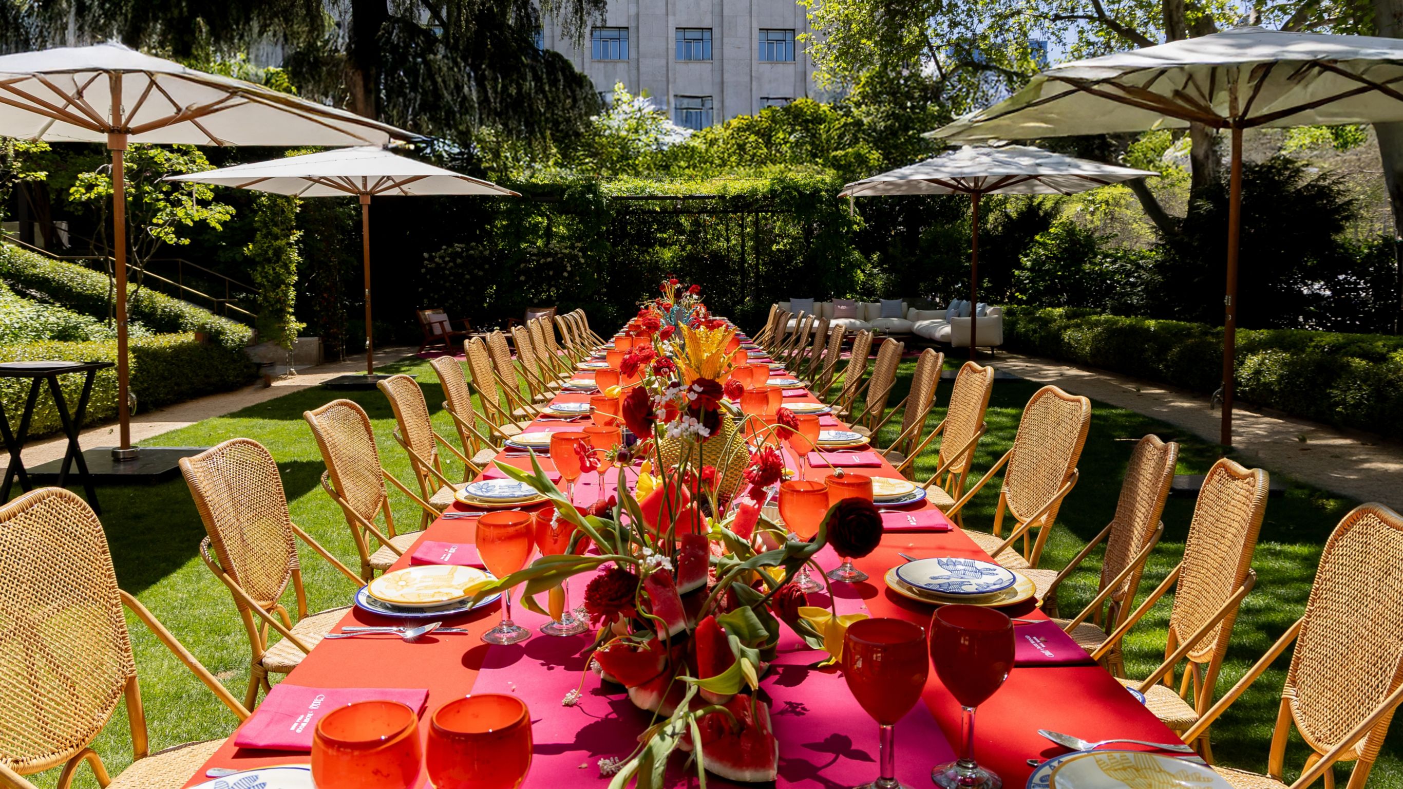 garden event setup with a boardroom table with red tablecloth sorrounded by plants and flowers